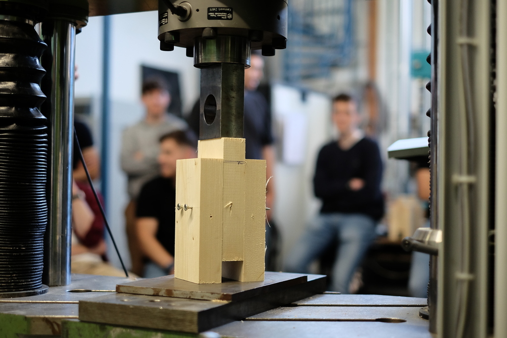 Prüfung der Druckfestigkeit eines Holzquaders in einer Materialprüfmaschine im Labor.